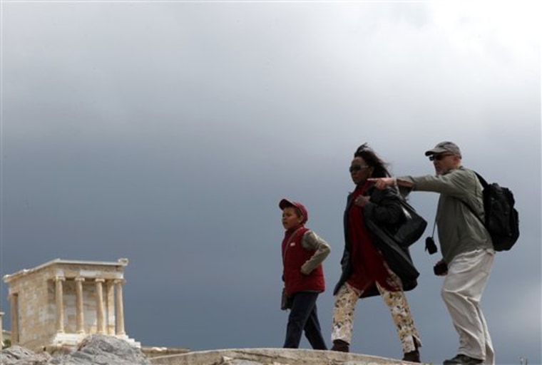 This Monday, April 18, 2011 photo shows tourists as they walk by the marble temple of Athena Nike in Athens, Greece. Many of Greece's tourists see the capital Athens as a simple launching pad for the beaches and cute whitewashed buildings of the islands. And the Aegean archipelago can be a great escape, especially during the nation's current economic crisis. But those willing to put Athens on their itinerary could be rewarded with bargains on everything from restaurants and hotels to souvenirs, if they are willing to step into the heart of the recession.   (AP Photo/ Petros Giannakouris)